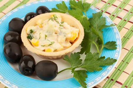 Tartlets with salad and olives on a blue plateの写真素材
