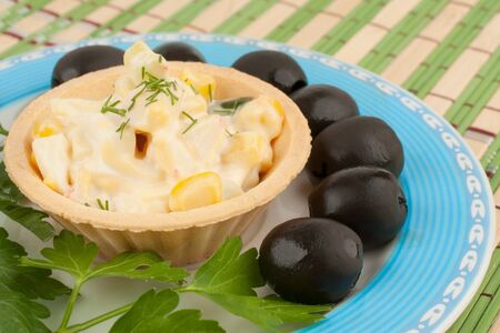 Tartlets with salad and olives on a blue plateの写真素材