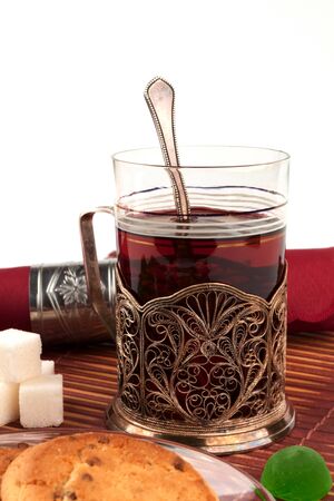 Glass of tea in the glass-holder and cookies in the foregroundの写真素材