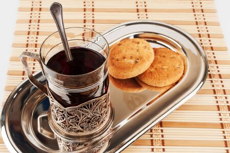 A cup of tea on a metal tray with two biscuitsの写真素材