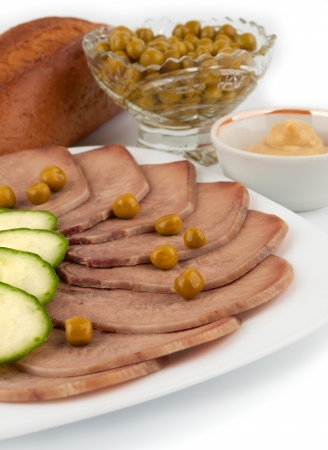 Slices of boiled beef tongue with green peas on white backgroundの写真素材