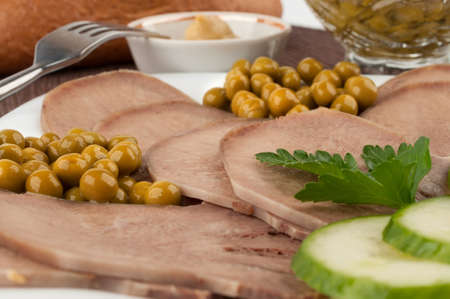 Slices of boiled beef tongue with green peasの写真素材
