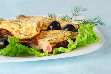 Slices of omelette on a plate  Against the background of a blue tableclothの写真素材