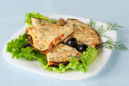 Slices of omelette on a plate  Against the background of a blue tableclothの写真素材
