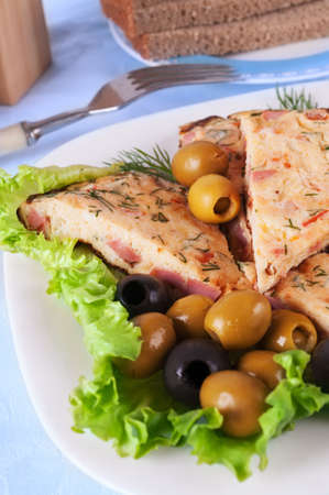 Omelet slices on lettuce leaves and several olives