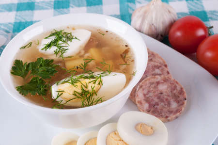 Vegetable soup decorated with slices of sausage and egg  On colored tableclothsの写真素材