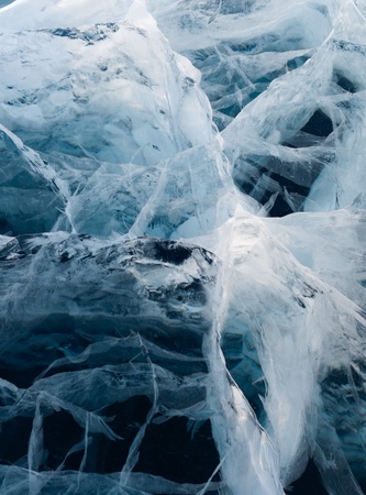 Network of cracks in thick solid layer of ice of a frozen riverの写真素材