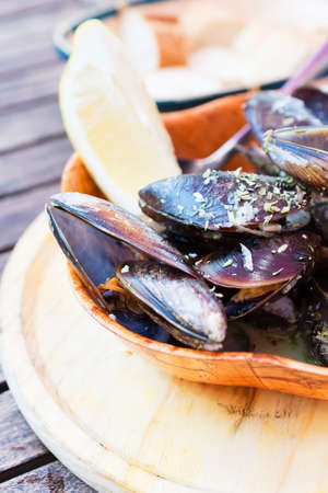 Cooked mussels in a bowl on a wooden tray の写真素材