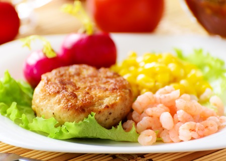 Chicken cutlets with canned corn and peeled shrimp  Served with fresh vegetables の写真素材