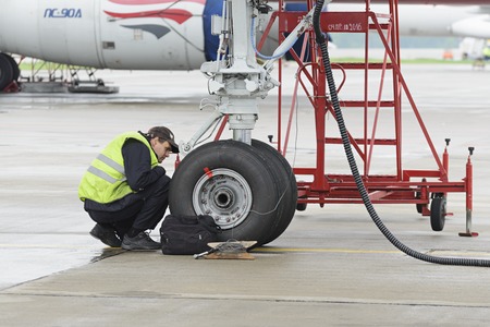 MOSCOW, RUSSIA - MAY 19, 2016: Aircraft  Tupolev-204 Red Wings airline in the parking lot of the international airport Domodedovo. The service engineer carry out work on inspection of the landing gear.のeditorial素材