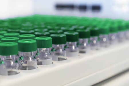 Rows of glass vials in the tray automatic liquid dispenser. Laboratory chemical equipments. Small...