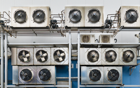 Industrial air conditioning units. A plurality of cooling units installed in the wall of a building.