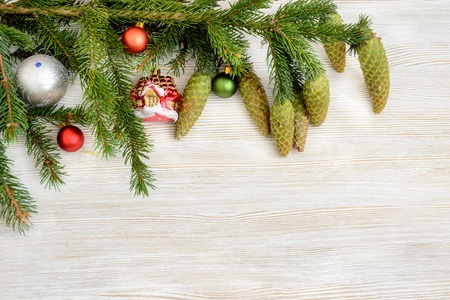 Christmas decorative background. Fur-tree branch with cones and Christmas balls on a blue wooden...