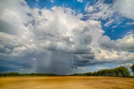 Thundercloud over a field. Because the cloud is heavy rain.の写真素材