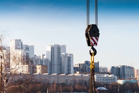 Hook suspension crane on the background of high-rise buildings. Abstract industrial background.の写真素材