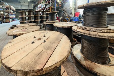 Large cable reels stocked in the factory premises. Workshop production of cable slings.の写真素材