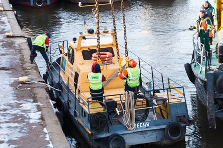 MOSCOW, RUSSIA - NOVEMBER 11, 2016: State Unitary Enterprise Mosvodostok performs recovery vessels on coastal winter parking. Workers slingers hooked to the vehicle chain slings.のeditorial素材