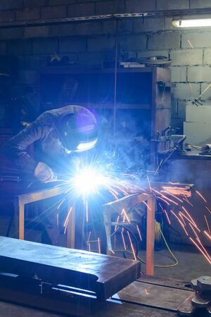 Working welder welds the parts at the factory. A process using a semi-automatic welding.