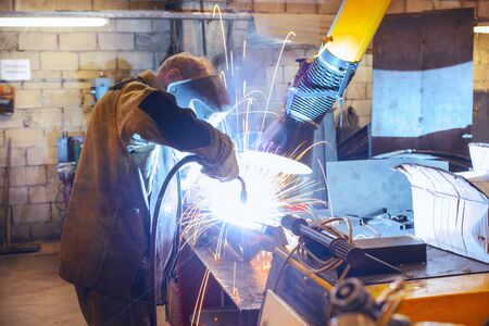Working welder welds the parts. A process using a semi-automatic welding.