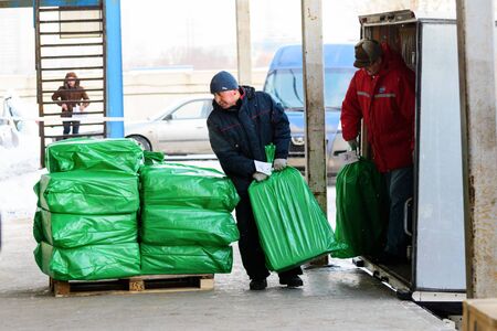 Worker puts on pallets loaded with green bags.のeditorial素材