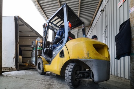 Forklift is putting cargo to truck outdoorsのeditorial素材