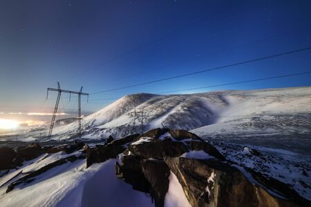 Support of the high-voltage line. A winter night mountain landscapeの写真素材