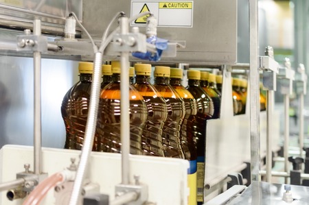Plastic bottles with beer on the conveyor of an automatic packing machine.の写真素材