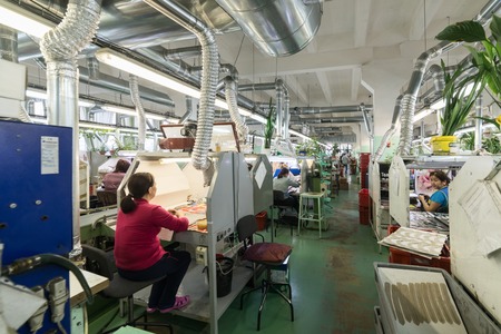 Shoe factory. Female worker on a sewing machine.のeditorial素材