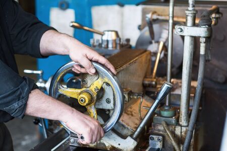 The hands of the turner rotate the wheel of the quill of the lathe.