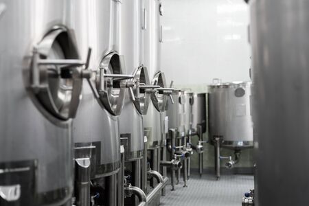 A lot of stainless steel tanks with large round hatches, modern beverage production.の写真素材