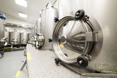 A lot of stainless steel tanks with large round hatches, modern beverage production.