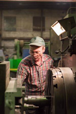 The turner processes the metal part on a mechanical lathe.のeditorial素材