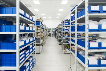 Industrial warehouse. White metal racks with blue plastic trays and cardboard boxes installed in them.の写真素材
