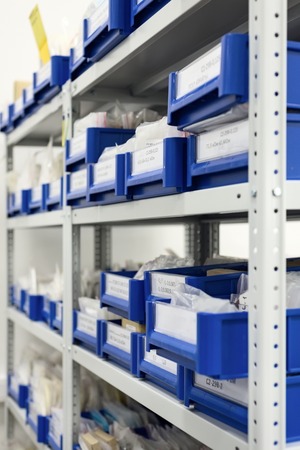 Industrial warehouse. White metal racks with blue plastic trays and cardboard boxes installed in them.の写真素材