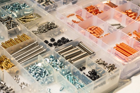 Many screws arranged as background. Metal fasteners, scattered in plastic cells.の写真素材