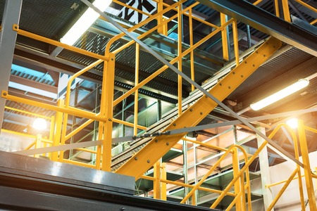 Metal staircase, with yellow railings and metal steps.