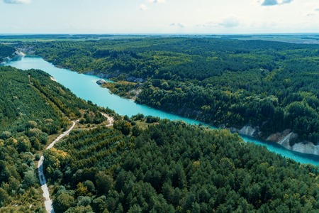 Abandoned mountain quarry. The mine workings are filled with water of a deep blue color. Aerial view