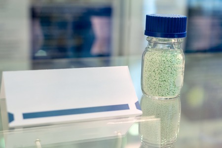 Glass jar with green granules. Nearby is a paper label without an inscriptionの写真素材