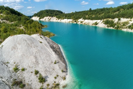 Very beautiful abandoned mountain quarry. The mine workings are filled with water of a deep blue color. Aerial viewの写真素材