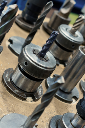 Metal drills, cutters, cones. Metal cutting tools installed in clamping chucks. Abstract industrial...