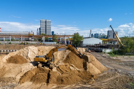 Tracked excavator overloads the sand from the embankment