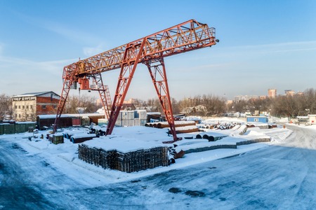 Open warehouse for storage of large diameter metal pipes. A gantry crane is installed in the territory. Winter sunny day.の写真素材