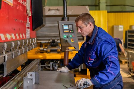 Worker works on a modern bending machine. CNC equipment for high-precision sheet metal bending.のeditorial素材