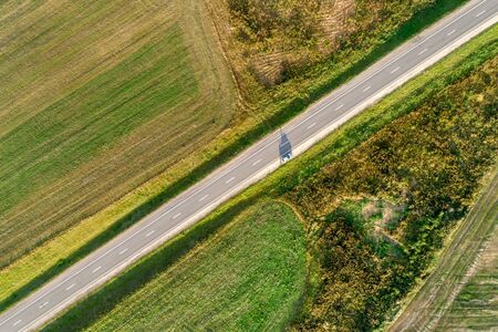 Asphalt highway passing through the field. Aerial view, vertically from top to bottomの写真素材