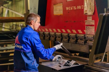 Worker works on a modern bending machine. CNC equipment for high-precision sheet metal bending.のeditorial素材