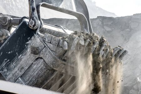 Powerful and large excavator bucket. Loading of minerals into the body of a mining truck.の写真素材
