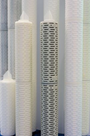 Large and long industrial filters. White high plastic cylinders with perforated wall.