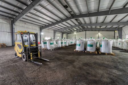 Large industrial warehouse of chemicals. Large white bags filled with powder are arranged in long...