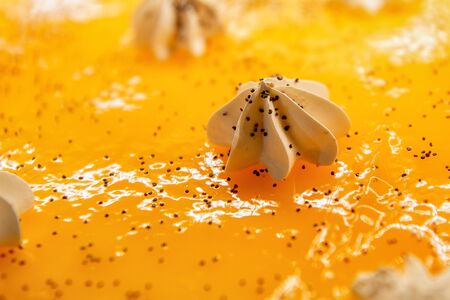 Cream curls on a big yellow cake. Confectionery decorations. Close-up shot.