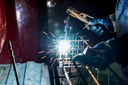 The welder welds steel reinforcement. Rebar assembly plant for reinforced concrete piles.